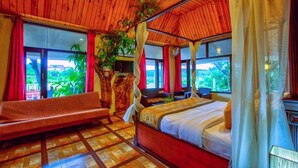 A bedroom with a bed, a sofa, and a large window.