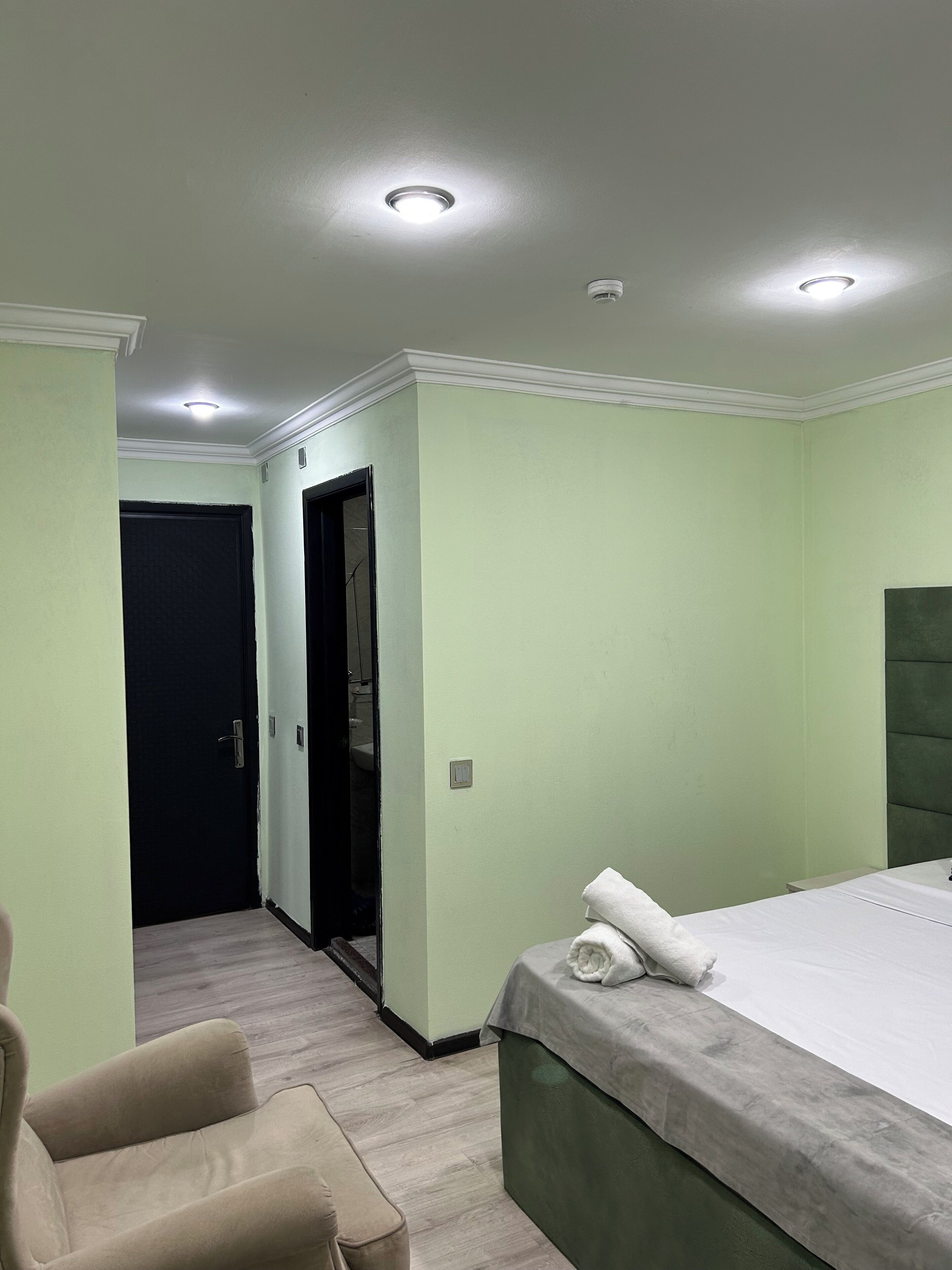 Ein Hotelzimmer mit einem Bett, einem Sessel, einer Tür und einer Deckenleuchte.