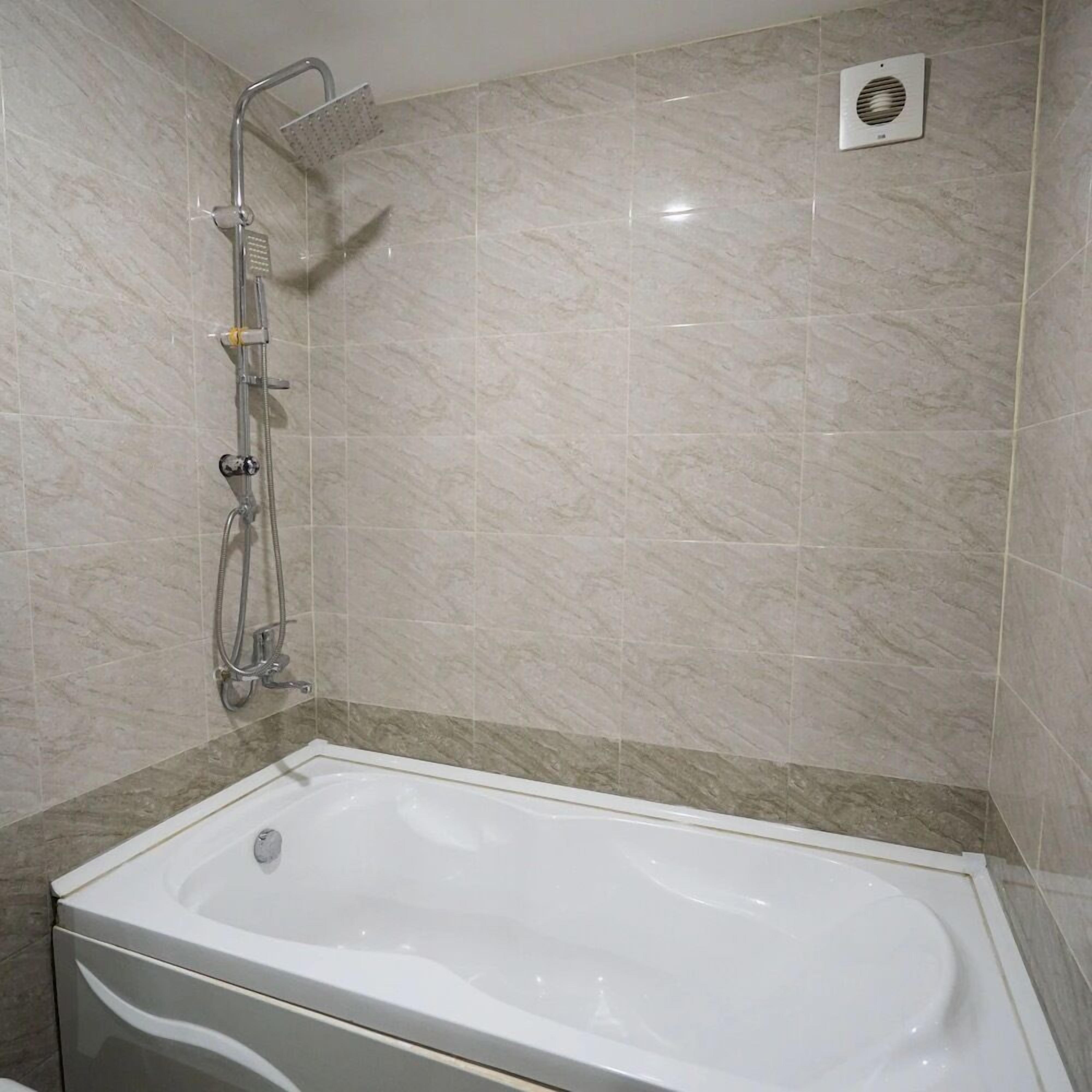 A bathroom with a bathtub, a shower, and a wall-mounted ventilation unit.