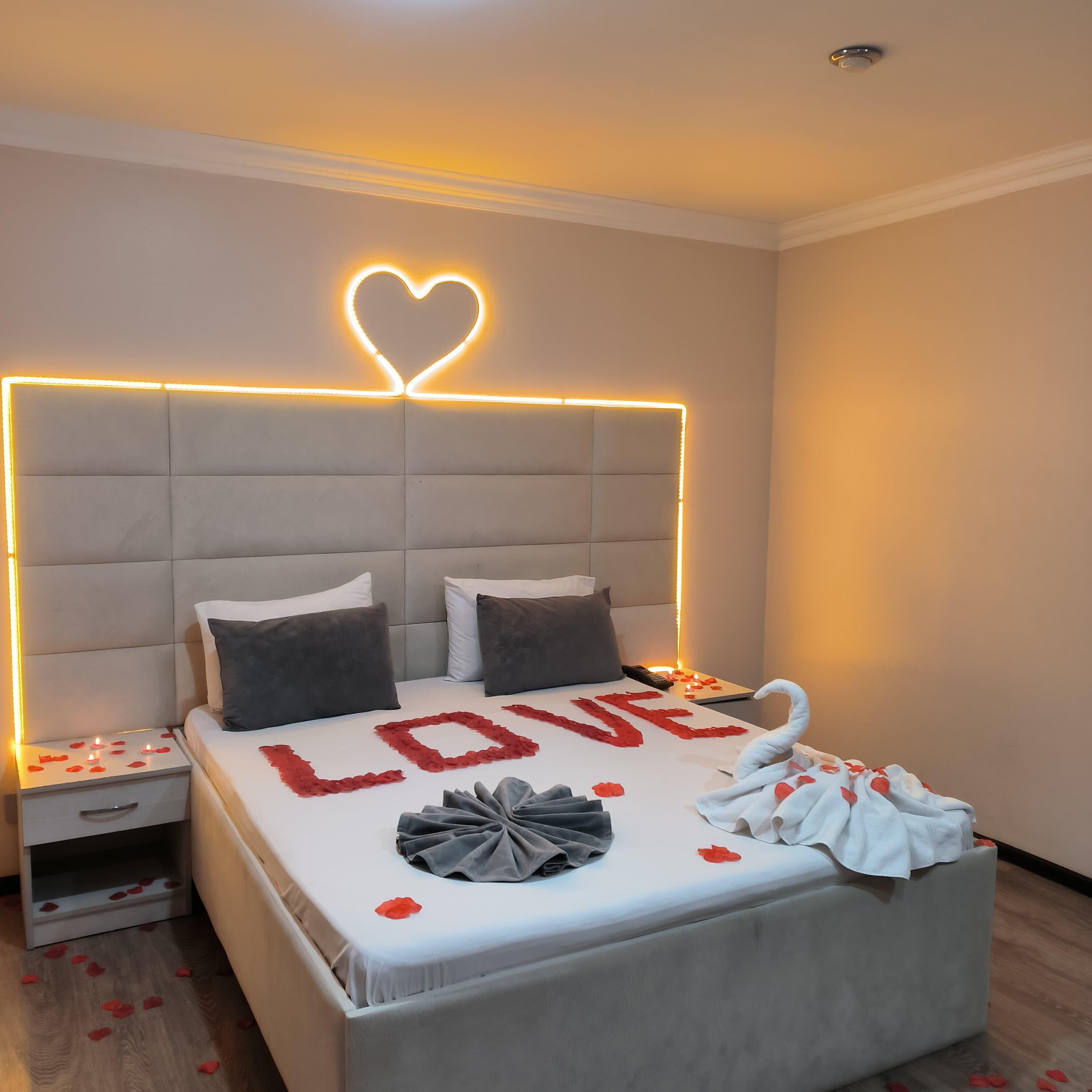A bedroom with a bed, a nightstand, and a wall-mounted light fixture.