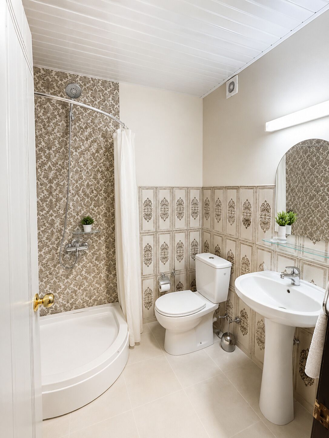 A bathroom with a bathtub, toilet, and sink, featuring patterned tiles and a mirror.
