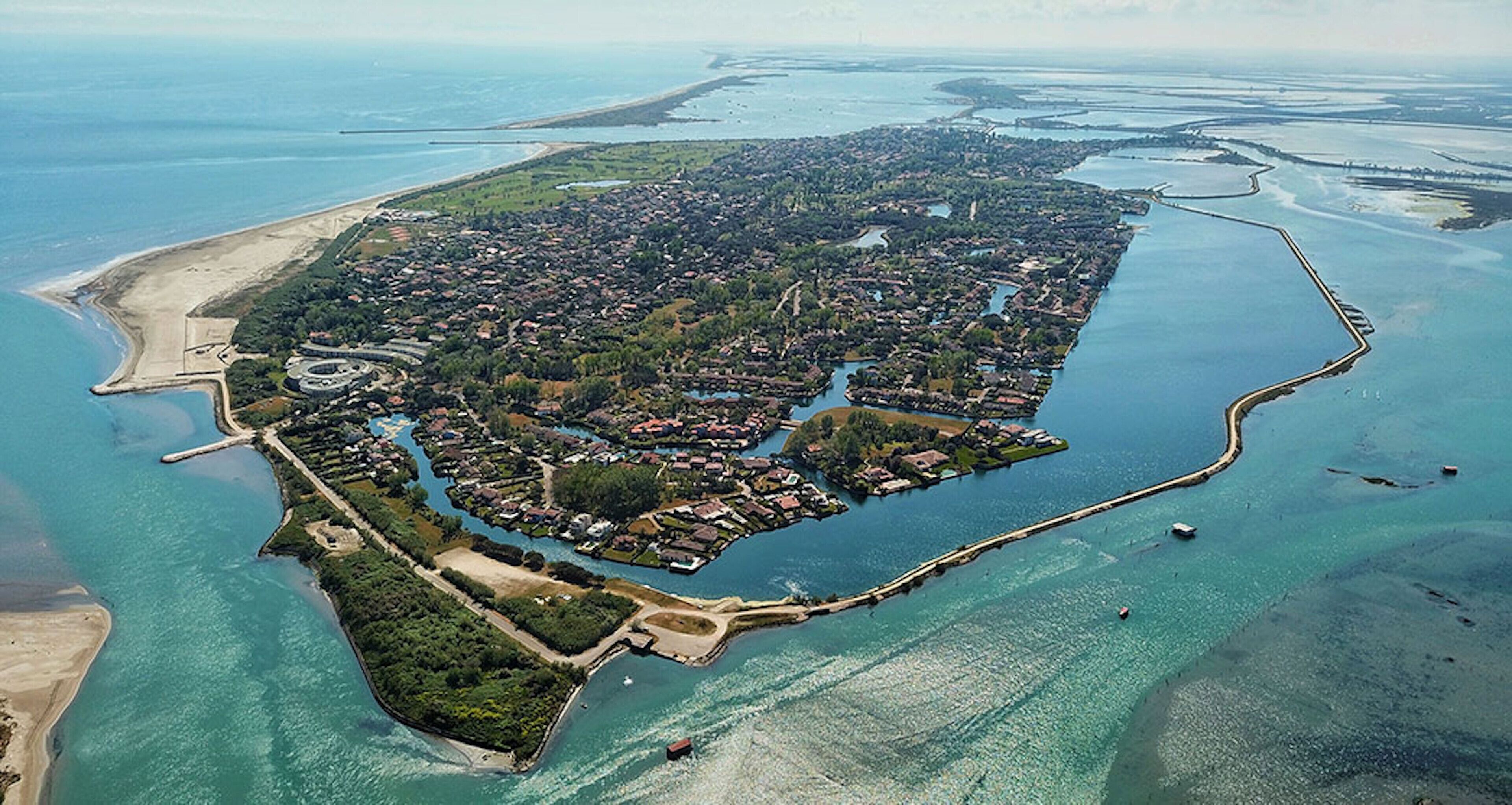 Vue aérienne d’une ville côtière avec une île centrale, entourée d’eau.