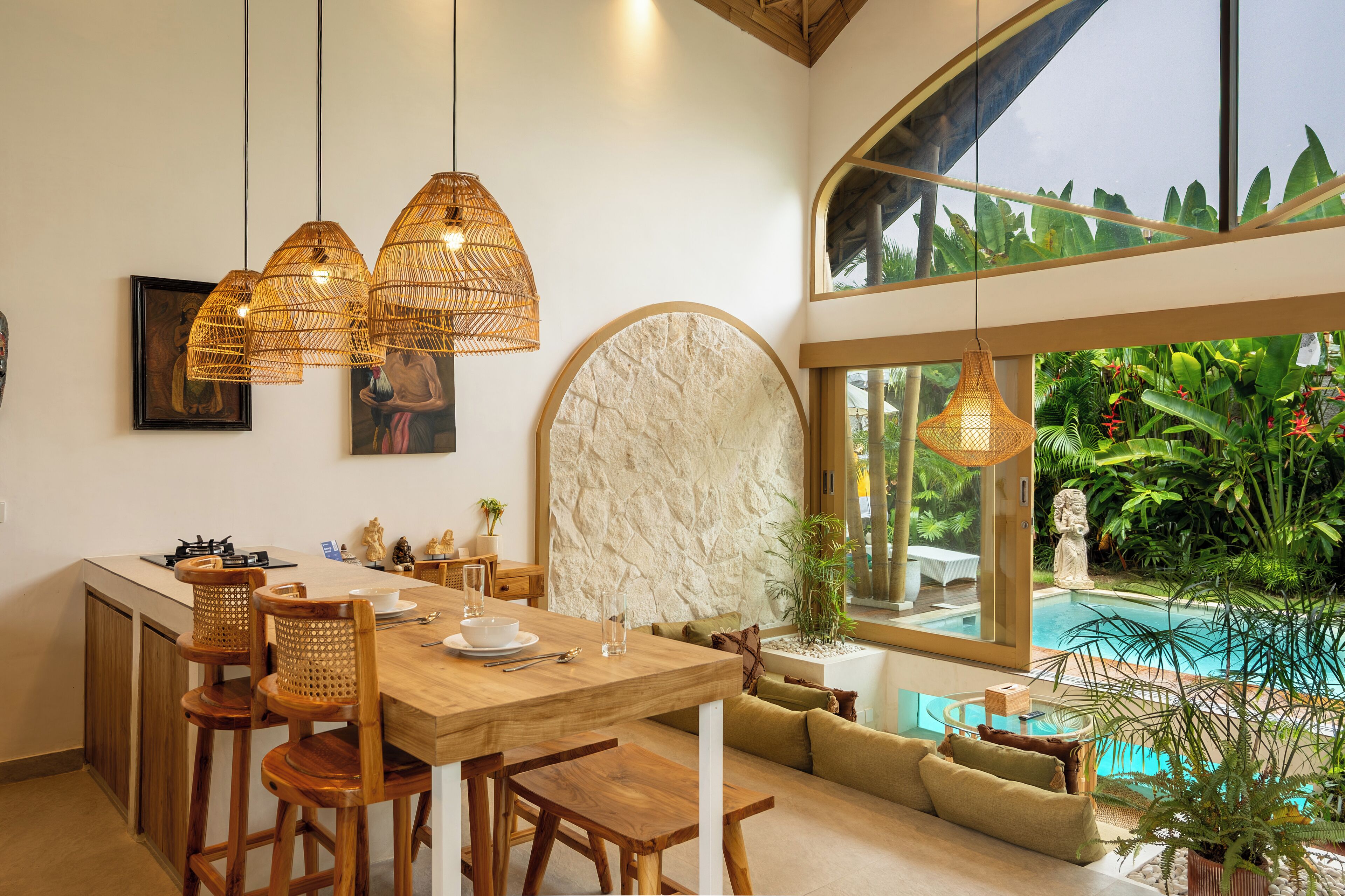 A modern kitchen with a wooden island, pendant lights, and a view of a pool.