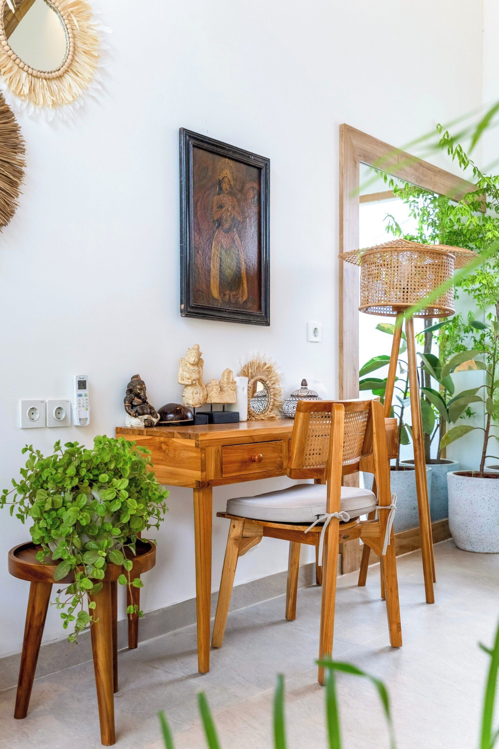 A wooden desk with a chair, a framed artwork, and a potted plant.