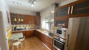 A kitchen with wooden cabinets, stainless steel appliances, a tiled backsplash, and pendant lighting. - Villa Bolet        . (Chiclana de la Frontera)