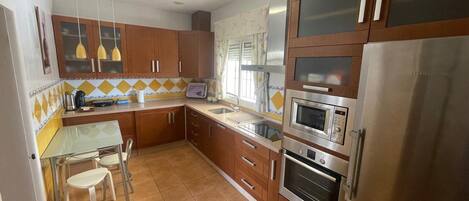A kitchen with wooden cabinets, stainless steel appliances, a tiled backsplash, and pendant lighting.