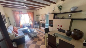 A living room with a sofa, TV, and a dining area with a table and chairs. - Villa Bolet        . (Chiclana de la Frontera)