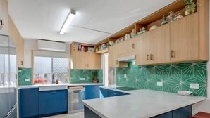 Een moderne keuken met blauwe kastjes, een centraal eiland en een groene, patrone backsplash.