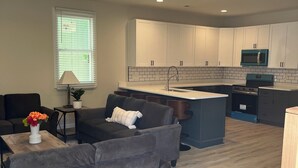 A modern kitchen with white cabinets, a central island, and a built-in microwave. - Downtown Escape - 5 blocks to Riverwalk (Wilmington)