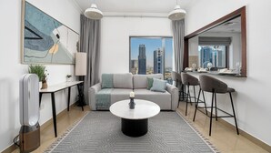 A modern living room with a sofa, coffee table, and bar stools. A large window offers a city view.