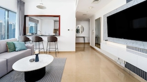 A modern living room with a sofa, a coffee table, and a large flat-screen TV mounted on the wall.
