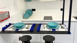 Een moderne keuken met witte kasten, een zwart aanrecht en blauw en turquoise servies.