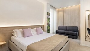 Una habitación de hotel moderna con una cama grande, un sofá y una mesita.