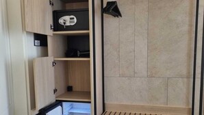 Un almacenamiento compacto con varios compartimentos, incluyendo un refrigerador pequeño, estantes y espacio para colgar.