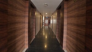 A corridor with wooden walls and a polished floor, leading to a door with a sign indicating room number 104. - Hotel Grand Maratha  (Nanded)