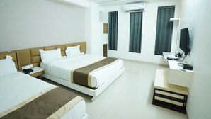 A modern hotel room with a large bed, a bedside table, a desk with a chair, a flat-screen TV, and an air conditioning unit. - Hotel Grand Maratha  (Nanded)