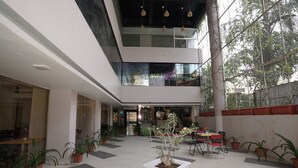 A spacious indoor area with multiple seating arrangements, potted plants, and a high ceiling with hanging lights. - Hotel Grand Maratha  (Nanded)