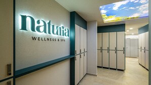 Un corridoio con un cartello che indica 'natura WELLNESS & SPA' e armadietti lungo la parete.