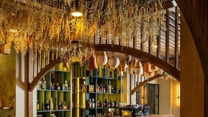 Un ristorante con un interno rustico, caratterizzato da travi in legno a vista, un'area bar in mattoni e sedie imbottite verdi.
