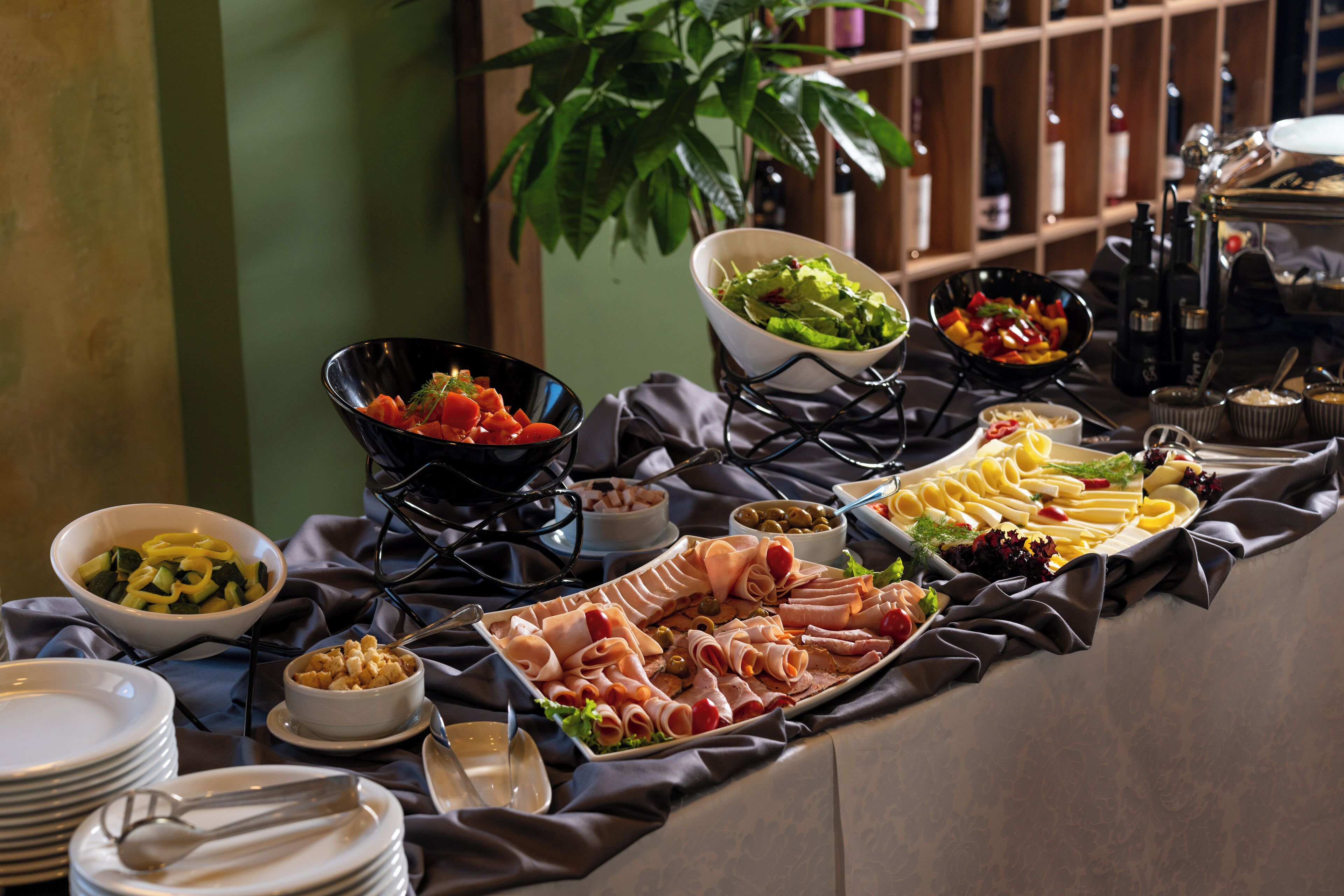 A buffet table with various food items and a potted plant in the background.