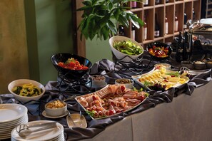 A buffet table with various food items and a potted plant in the background. - Valedor Hotel Boutique&SPA (Busteni)