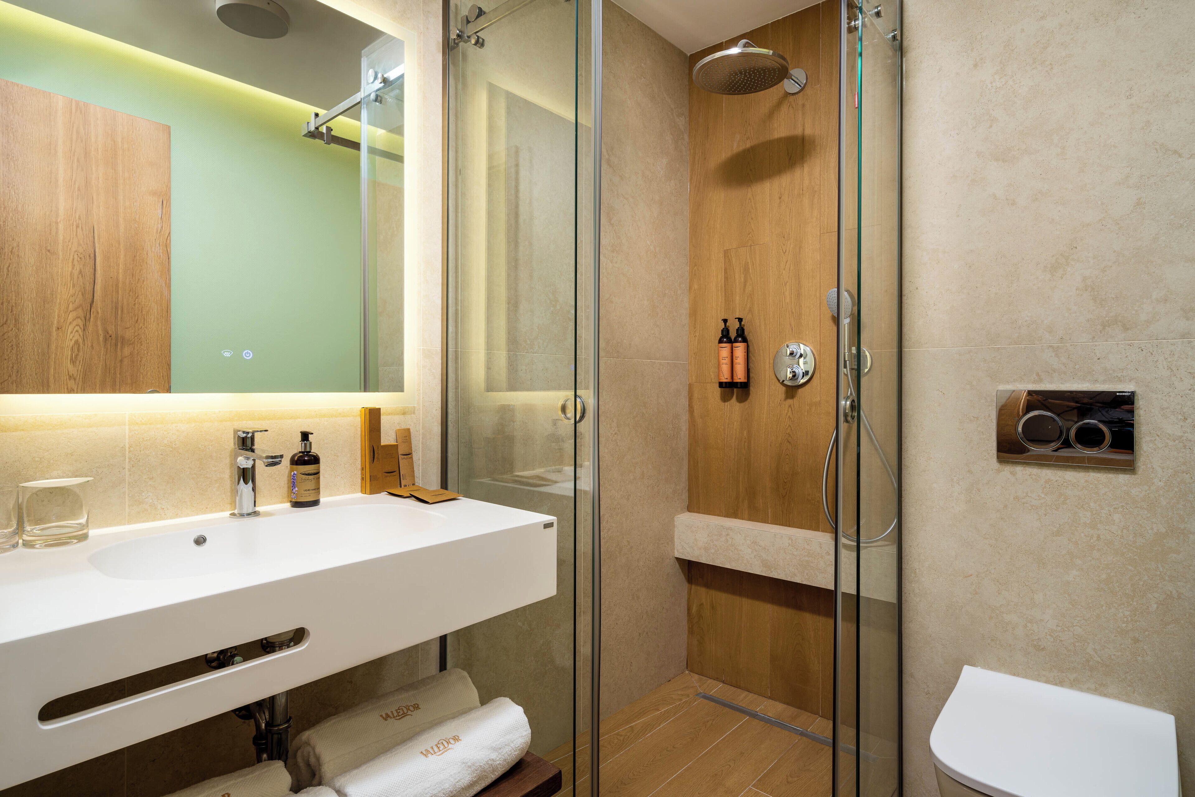 A modern bathroom with a glass-enclosed shower, a white sink, and a toilet.