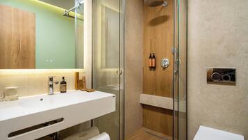 A modern bathroom with a glass-enclosed shower, a white sink, and a toilet.