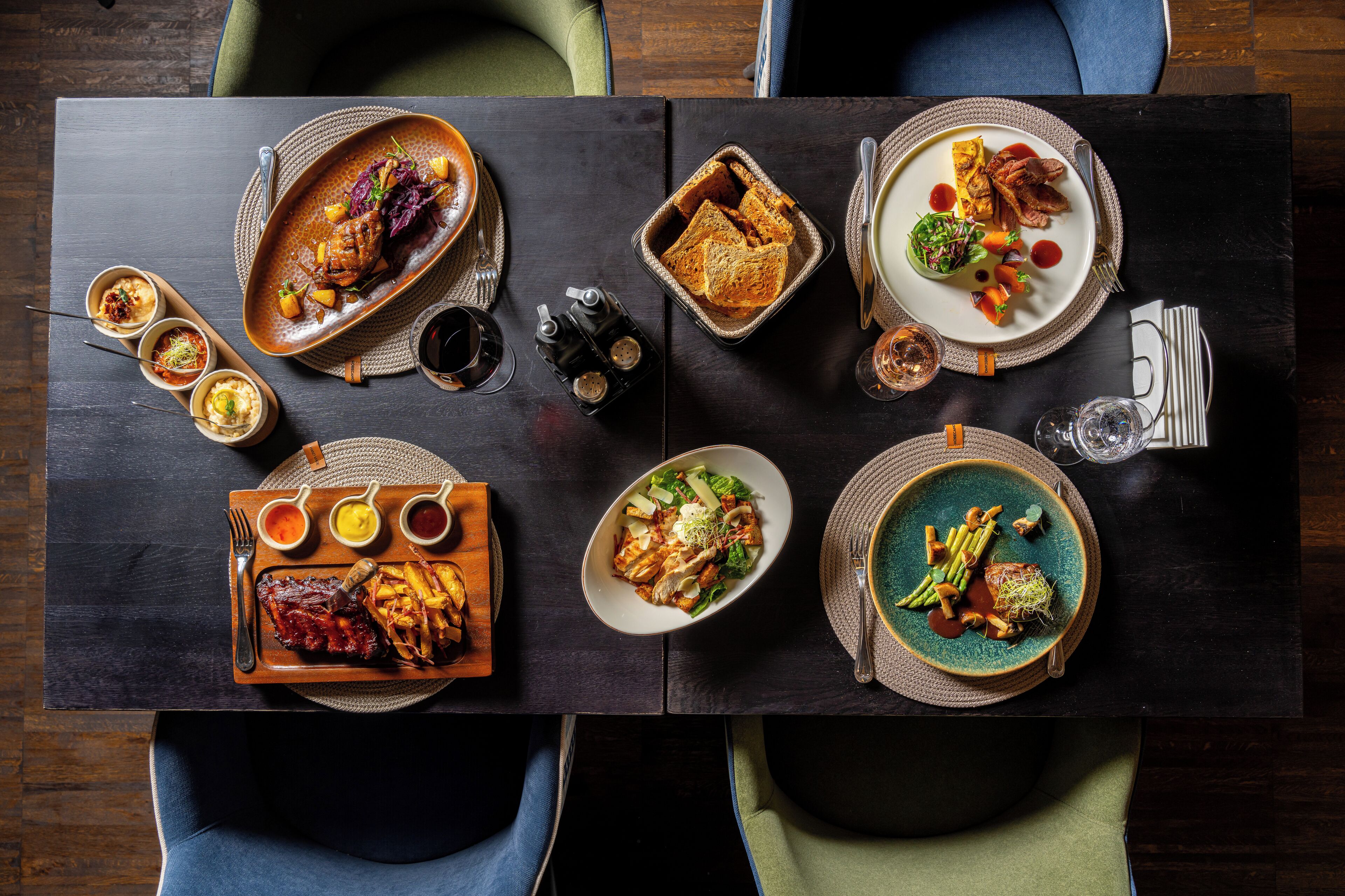 A dining table with various dishes and drinks, surrounded by chairs.
