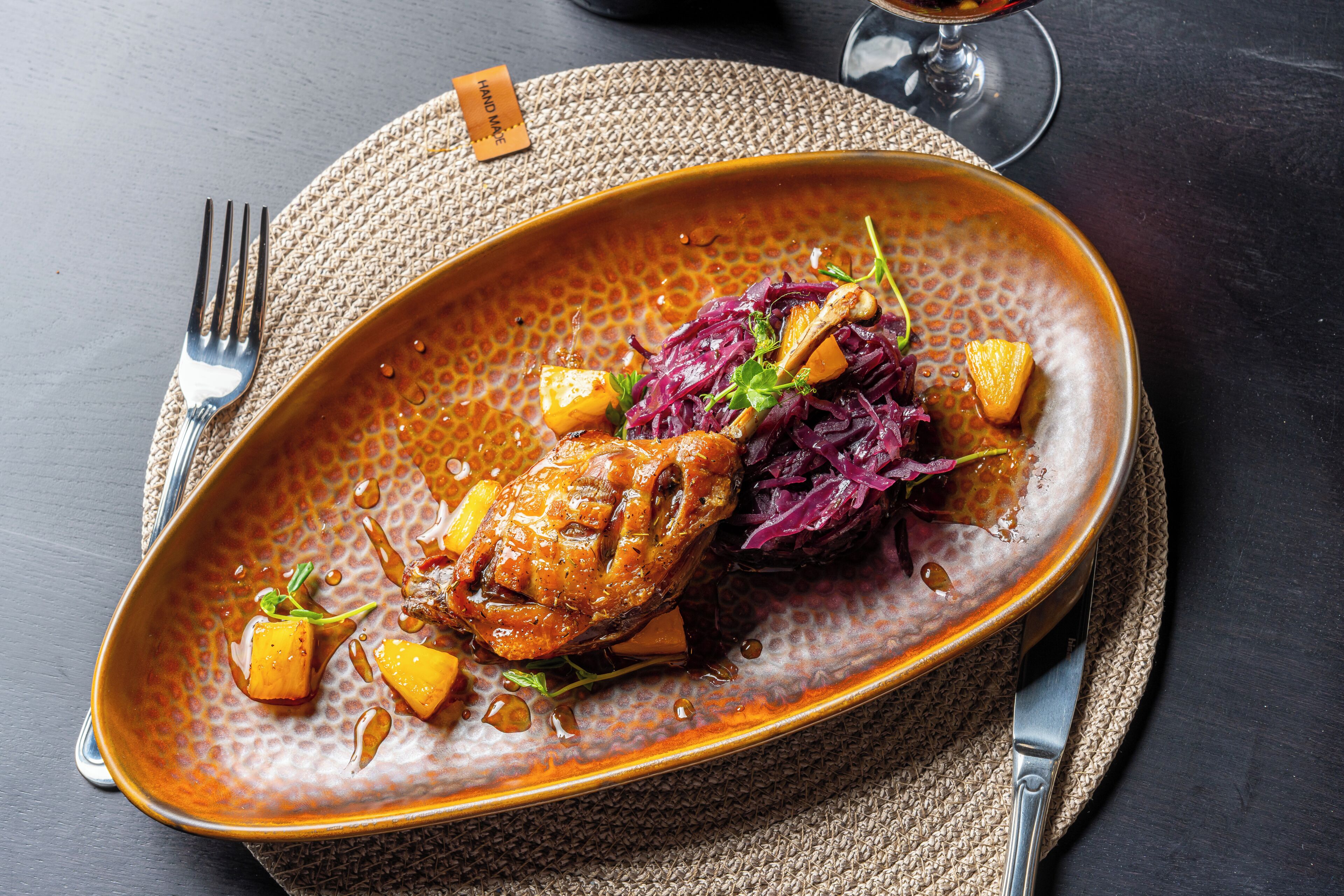 A ceramic plate with a roasted chicken, red cabbage, and pineapple chunks.