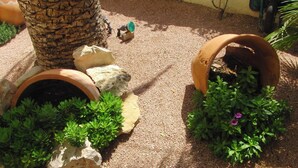 Un jardin agrémenté de pots en terre cuite, de rochers et de plantes vertes.