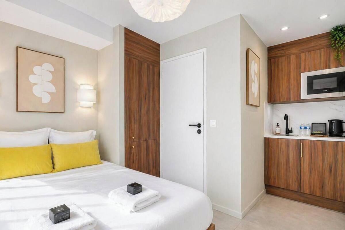 A hotel room with a bed, bedside lamps, a microwave, and a small kitchenette.