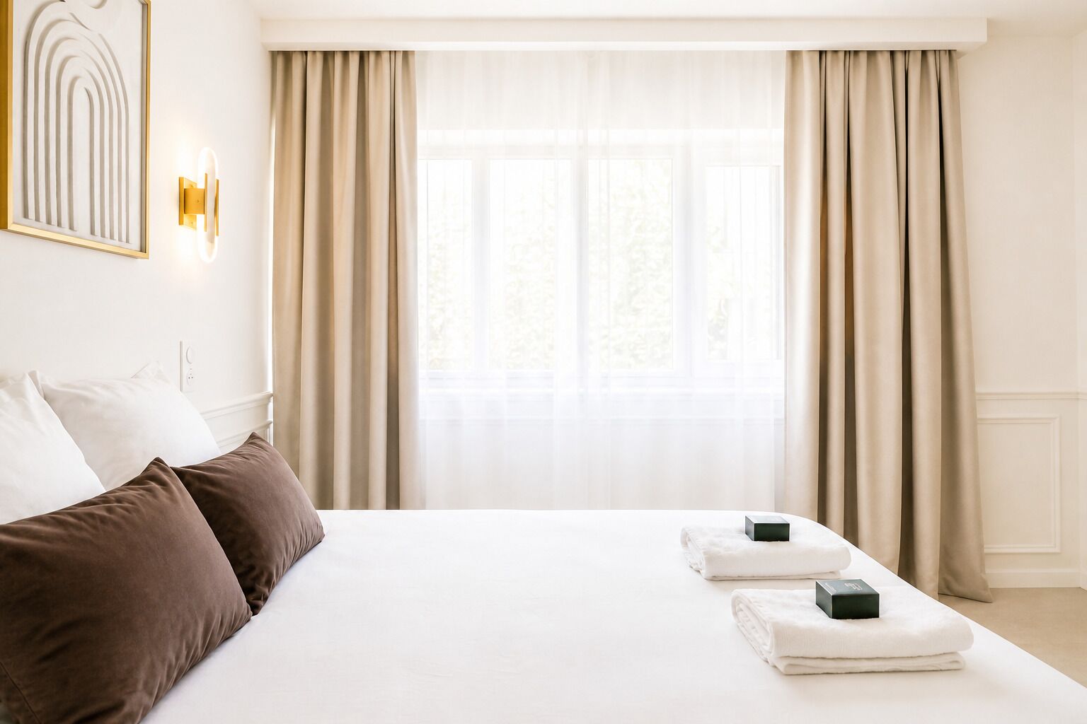 Een hotelkamer met een groot bed, beige gordijnen en een kunstwerk in een lijst aan de muur.