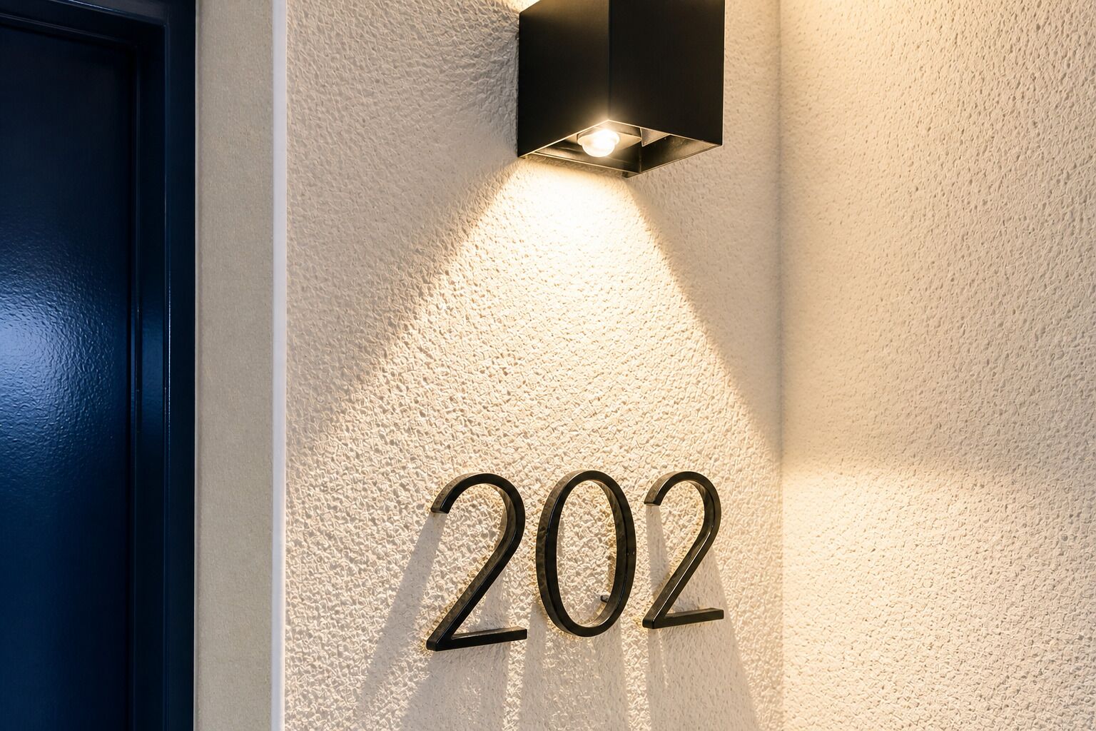 El número de casa '202' il·luminat per un llum de paret.