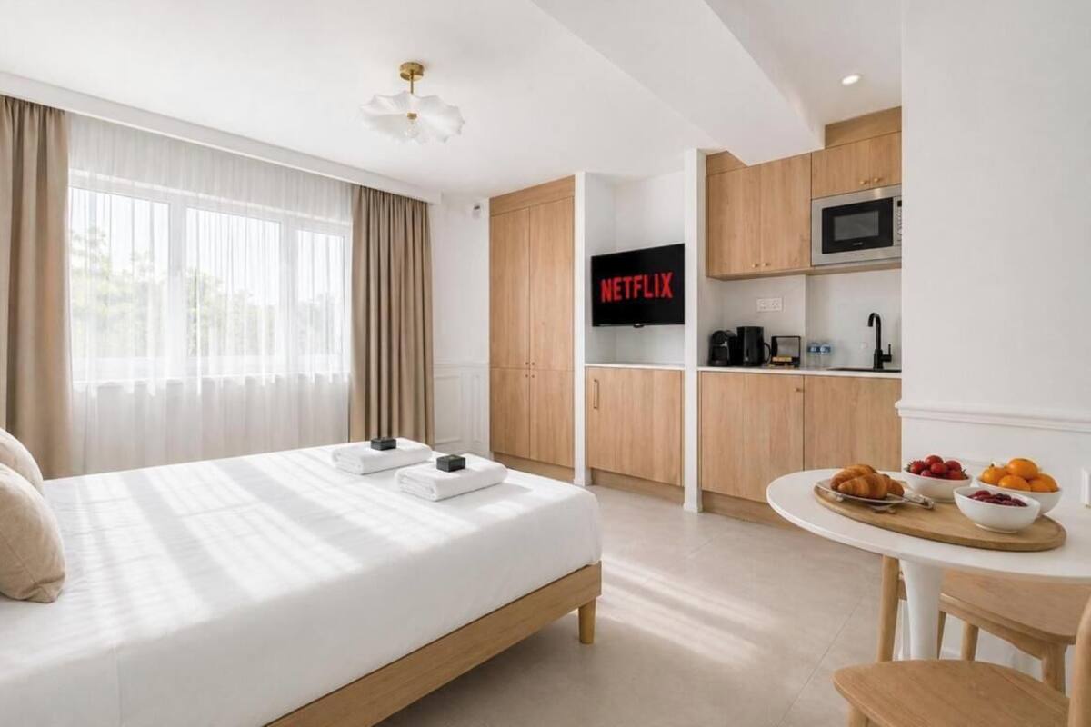 A hotel room with a bed, a TV, a kitchenette, and a dining area.
