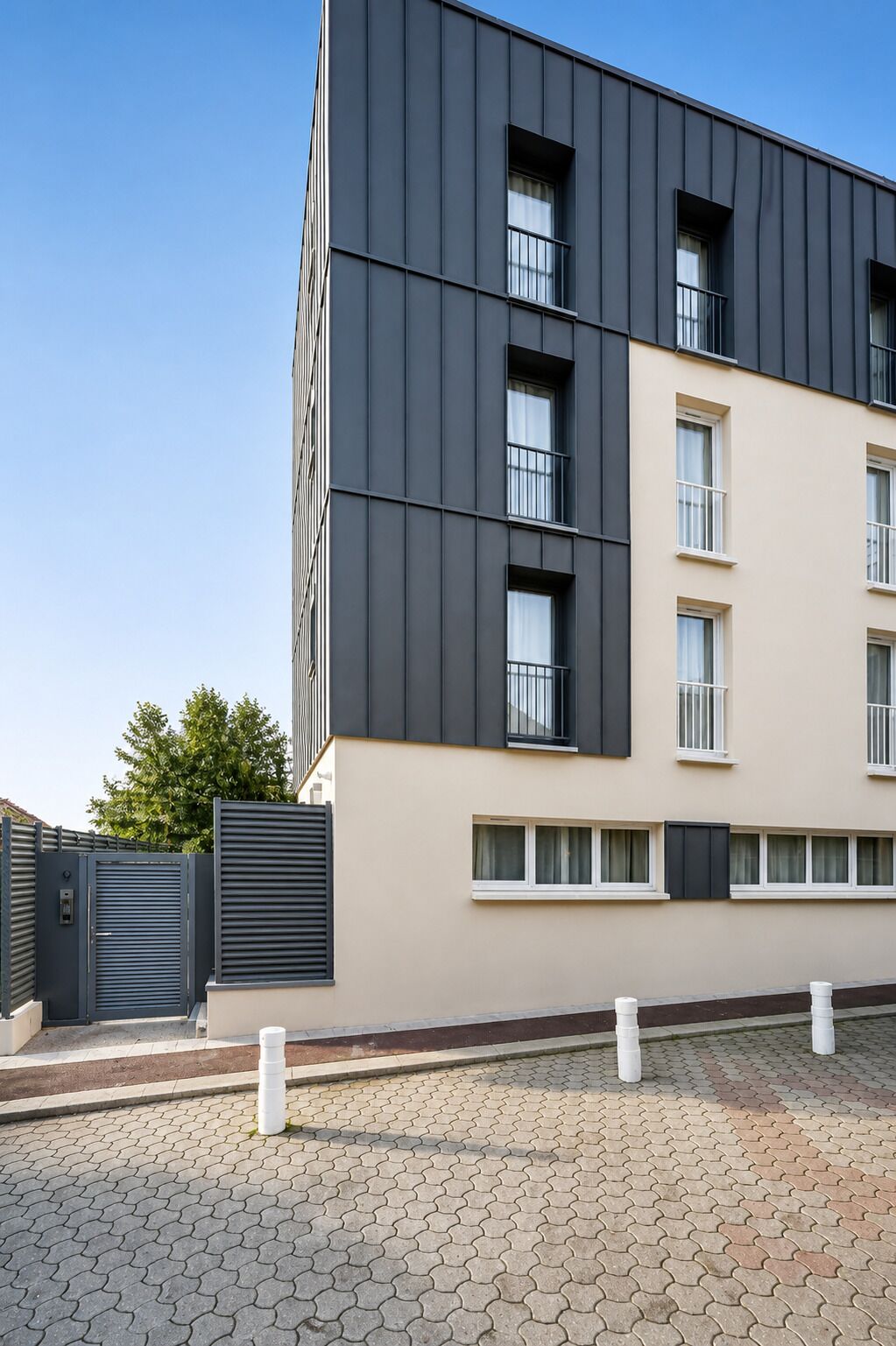 A modern multi-story building with a flat roof, large windows, and a gated entrance.