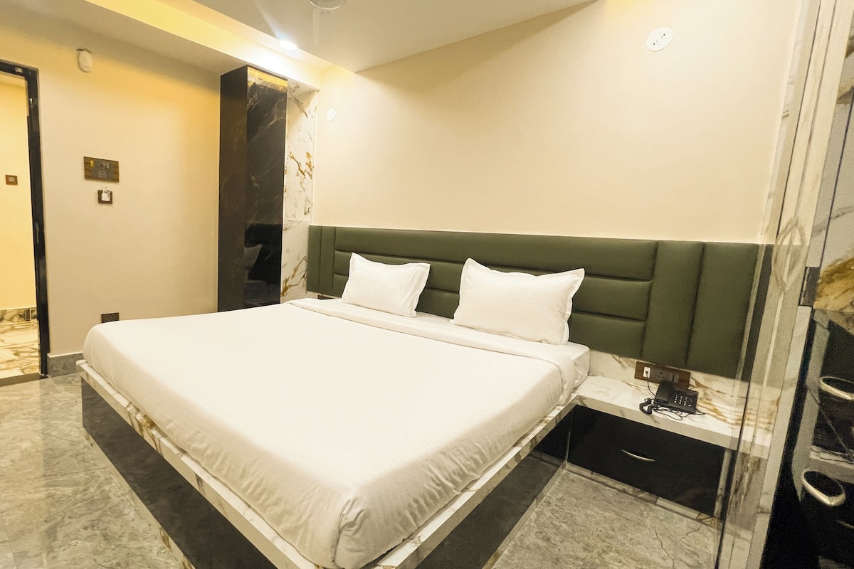Una habitación de hotel moderna con una cama grande, una mesita de noche y suelo de mármol.