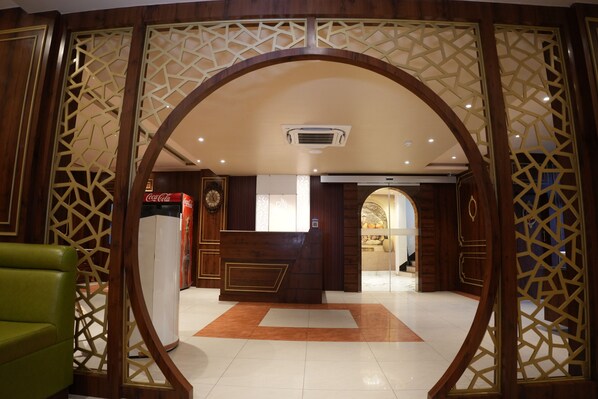A reception area with a wooden reception desk, a Coca-Cola refrigerator, and a decorative archway. - Roop Vihar Resort (Bhagalpur)