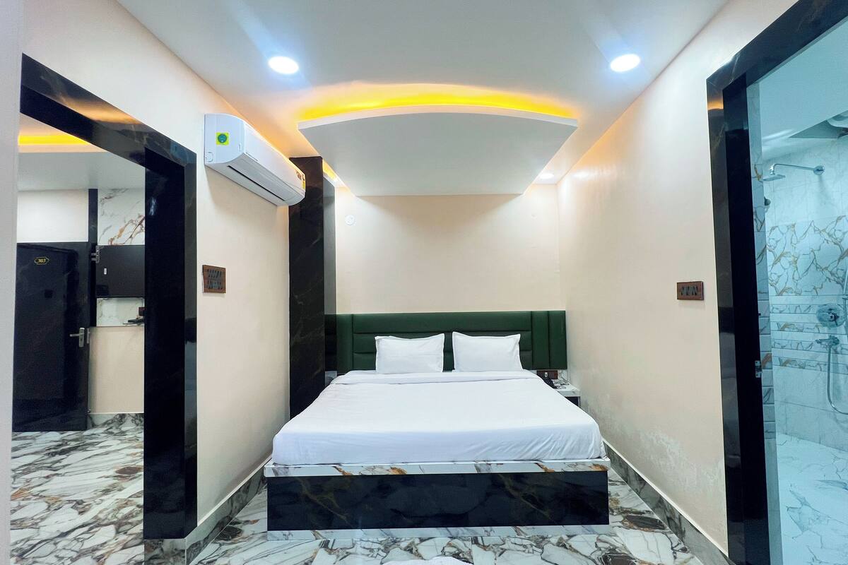 Habitación de hotel con cama, ducha y piso de mármol.