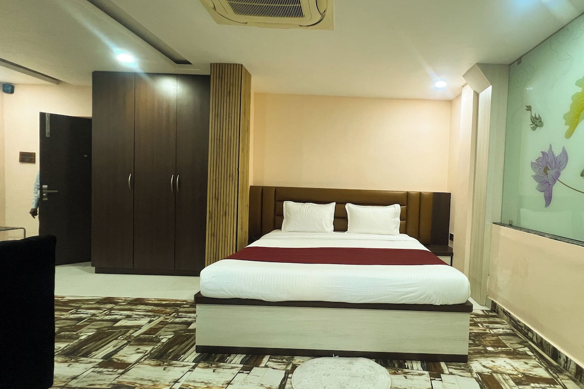 Una habitación de hotel con una cama, un armario, un espejo y una pared con papel tapiz floral.
