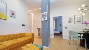 Una sala moderna con un sofá amarillo, un sillón color turquesa y un suelo de madera con diseño espiga.