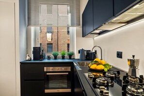 A modern kitchen with a built-in oven, a gas stove, and a window overlooking a brick building.