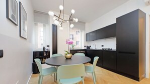 Cocina compacta con electrodomésticos modernos, comedor con mesa redonda y sillas, y vista a la calle.