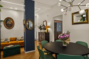 A modern living room with a sofa, a dining table with chairs, and a large mirror.