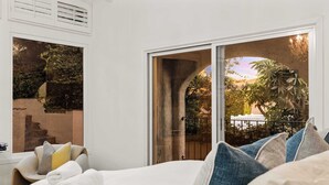 A hotel room with a bed, pillows, and a view of a garden through a glass door. - @Marbella Lane - Home w/ Ocean & Golf Course Views (San Clemente)