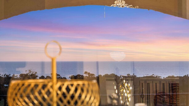 A view through a window with a decorative bowl in the foreground, a clear sky, and a distant shoreline. - @Marbella Lane - Home w/ Ocean & Golf Course Views (San Clemente)