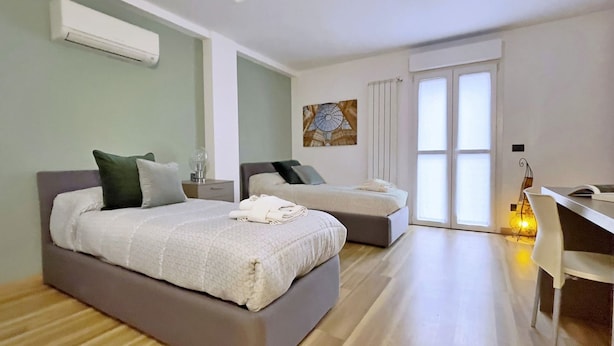 A modern bedroom with two beds, a desk, and a large window. - Apt With Gym in Bovisa Milan (Milan)