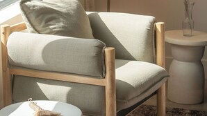A modern living room with a wooden chair, a round side table, and a floor lamp.
