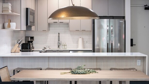 A modern kitchen with a large island, stainless steel appliances, and a pendant light.