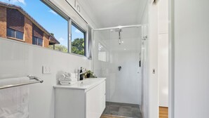 A modern bathroom with a glass shower enclosure, a white vanity, and a towel rack.