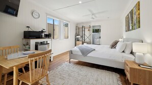 A modern bedroom with a bed, bedside table, and a desk area with a microwave and coffee maker.